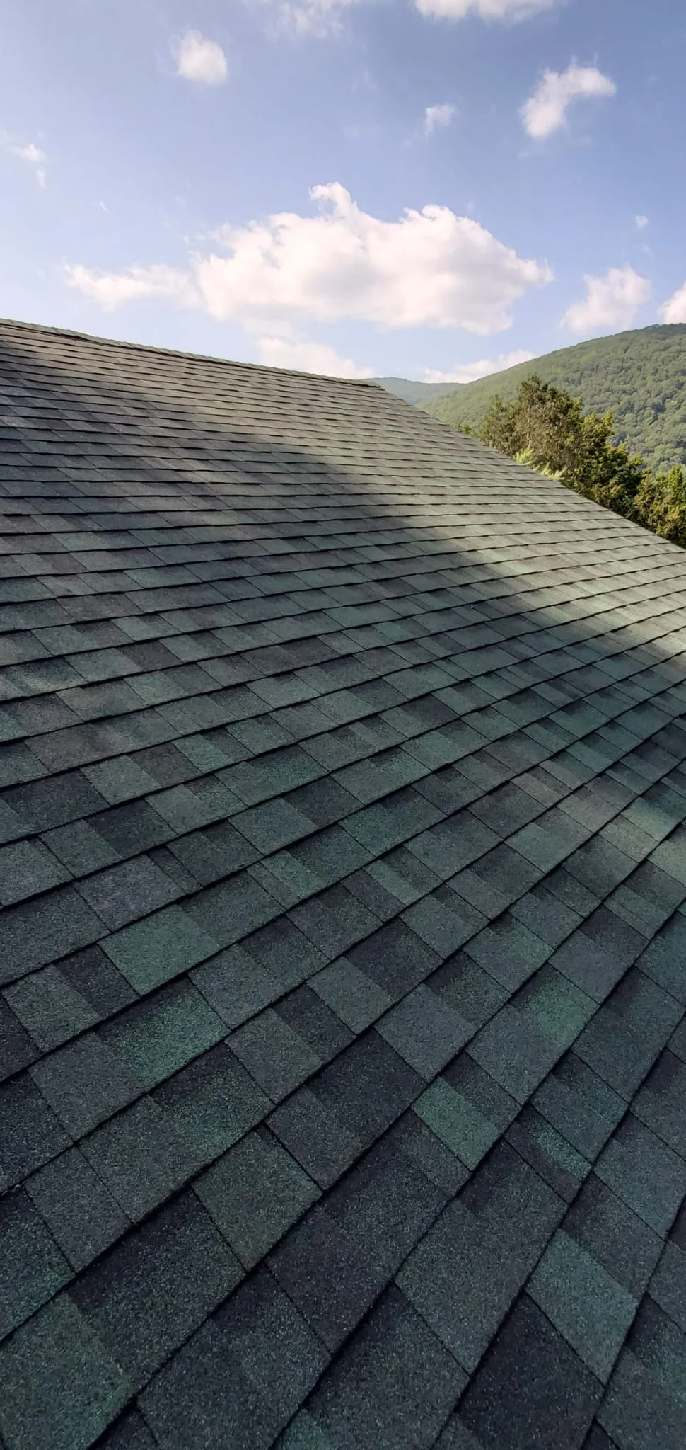 Newly installed architectural asphalt shingles in charcoal gray on steep pitched roof