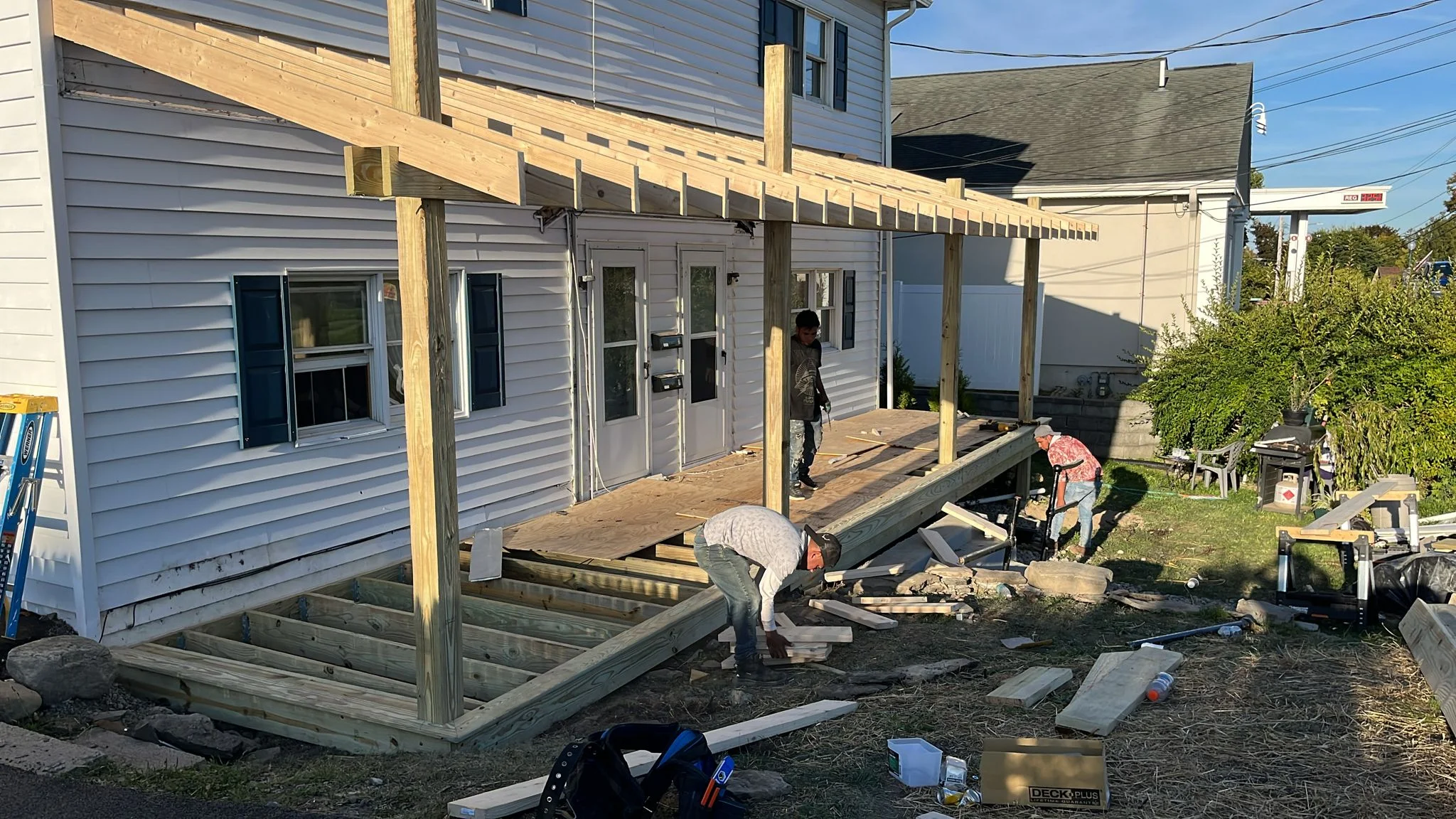 Pressure-treated wood deck with pergola under construction, timber framing and concrete footings visible