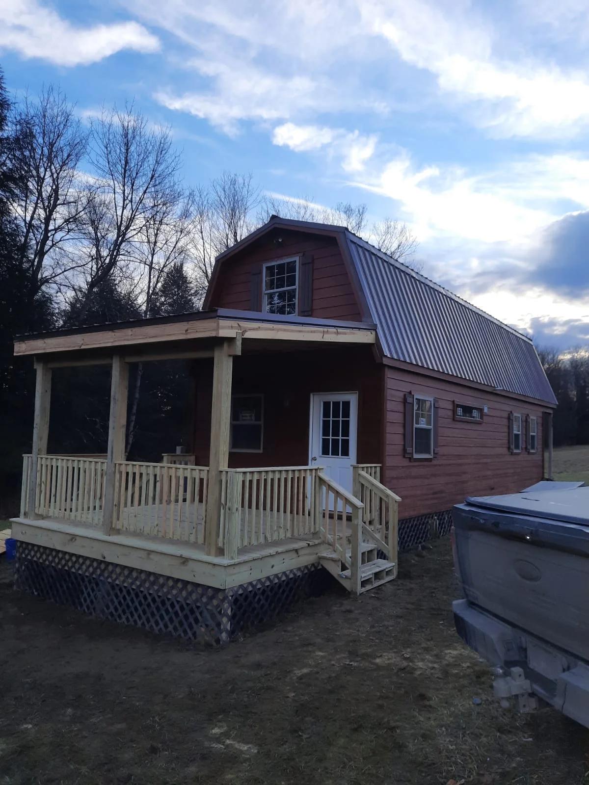 Red barn-style home with metal roof, white porch railings, and multiple windows