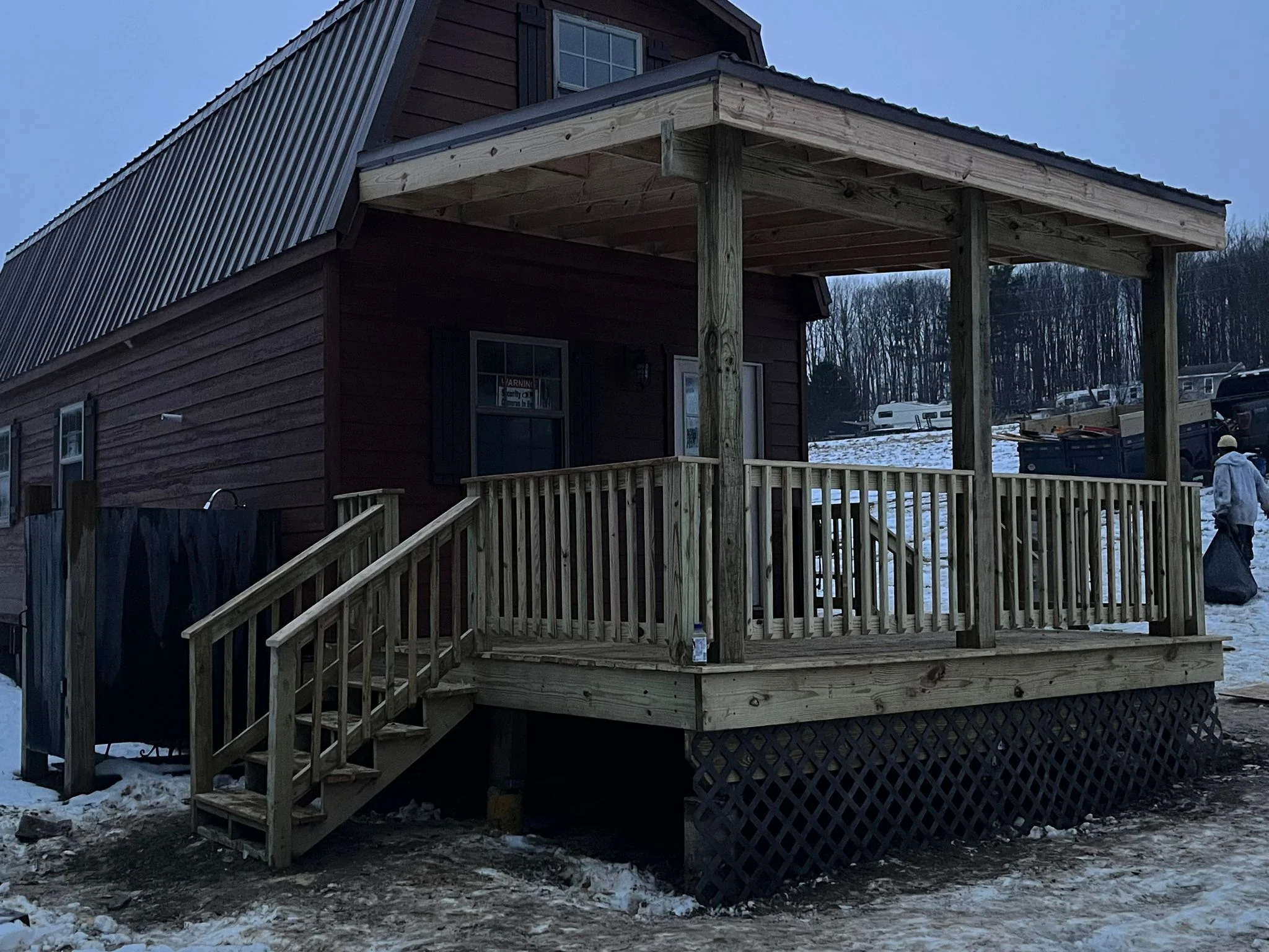 Covered porch with wood railings, gable roof, and pressure-treated deck framing