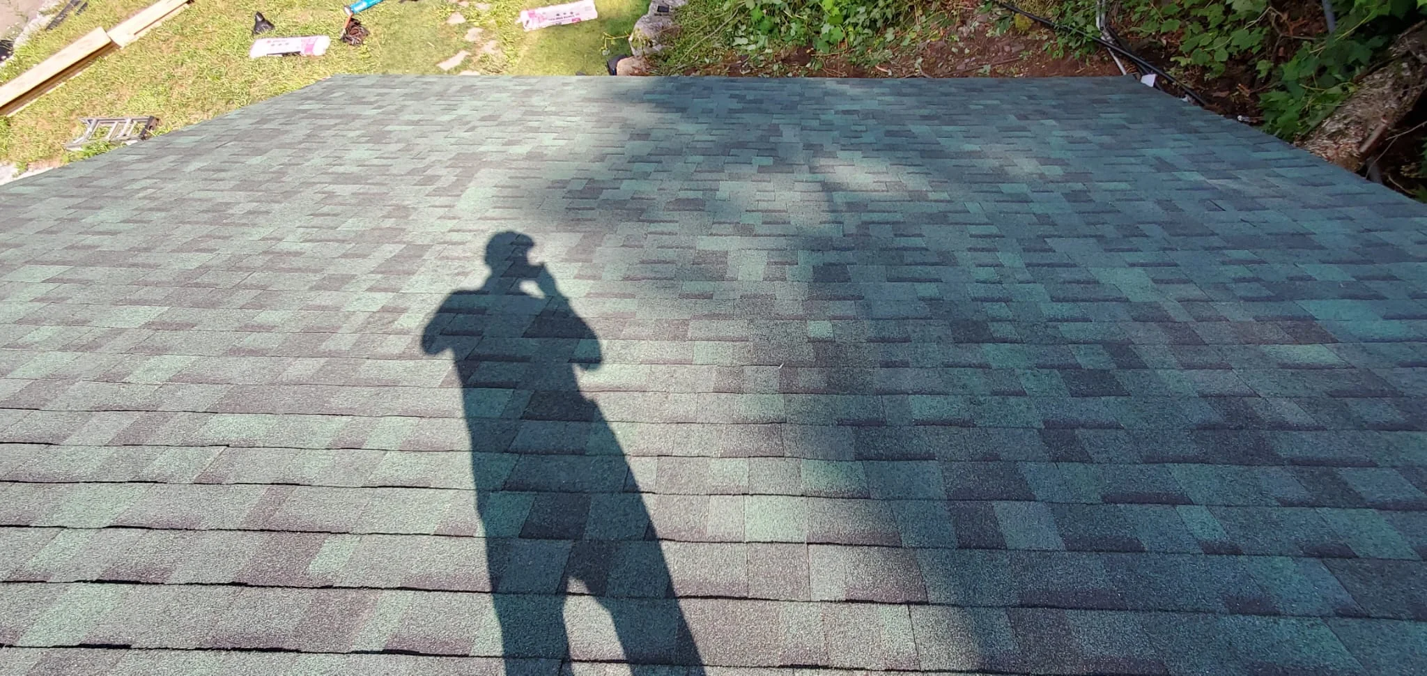 Newly installed architectural shingles in slate and charcoal colors with staggered pattern layout