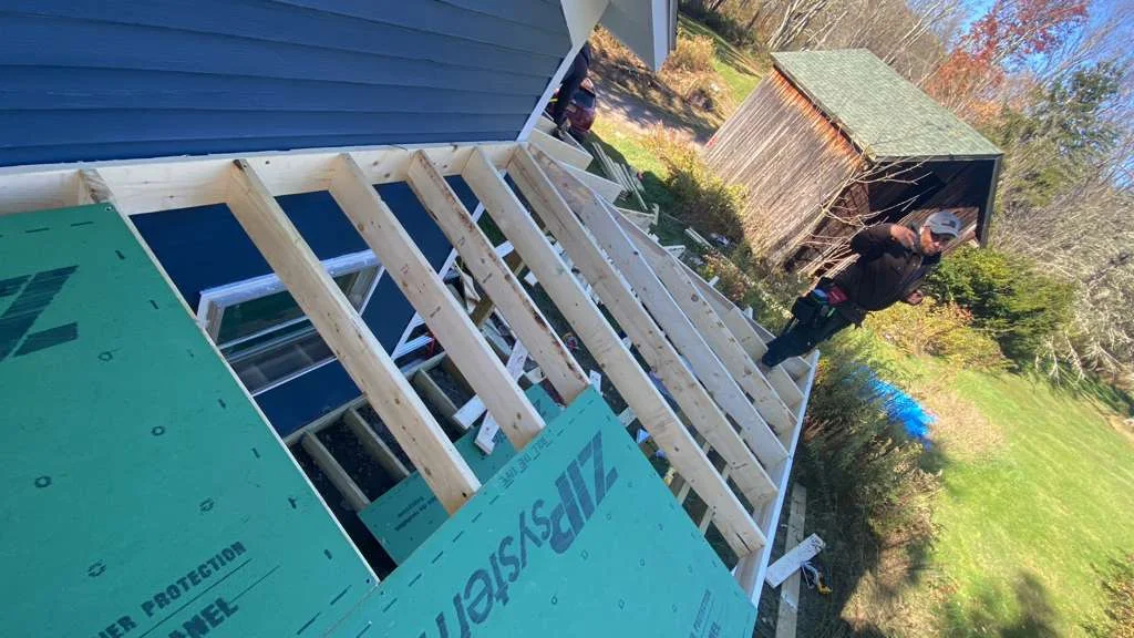 Roof framing with lumber rafters and turquoise weather protection sheathing during construction
