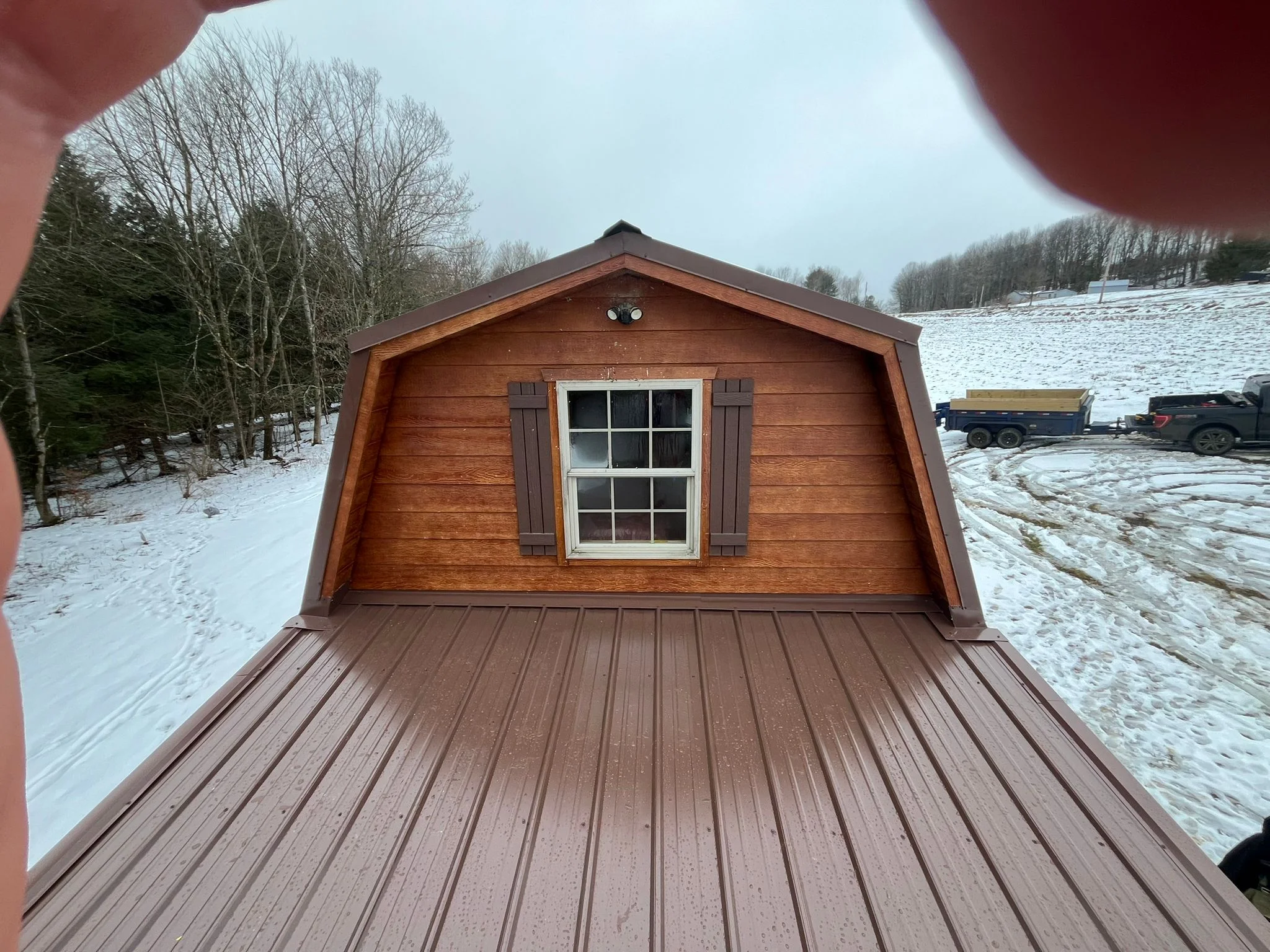 Wooden barn-style storage building with metal roof, wood siding, and metal deck flooring