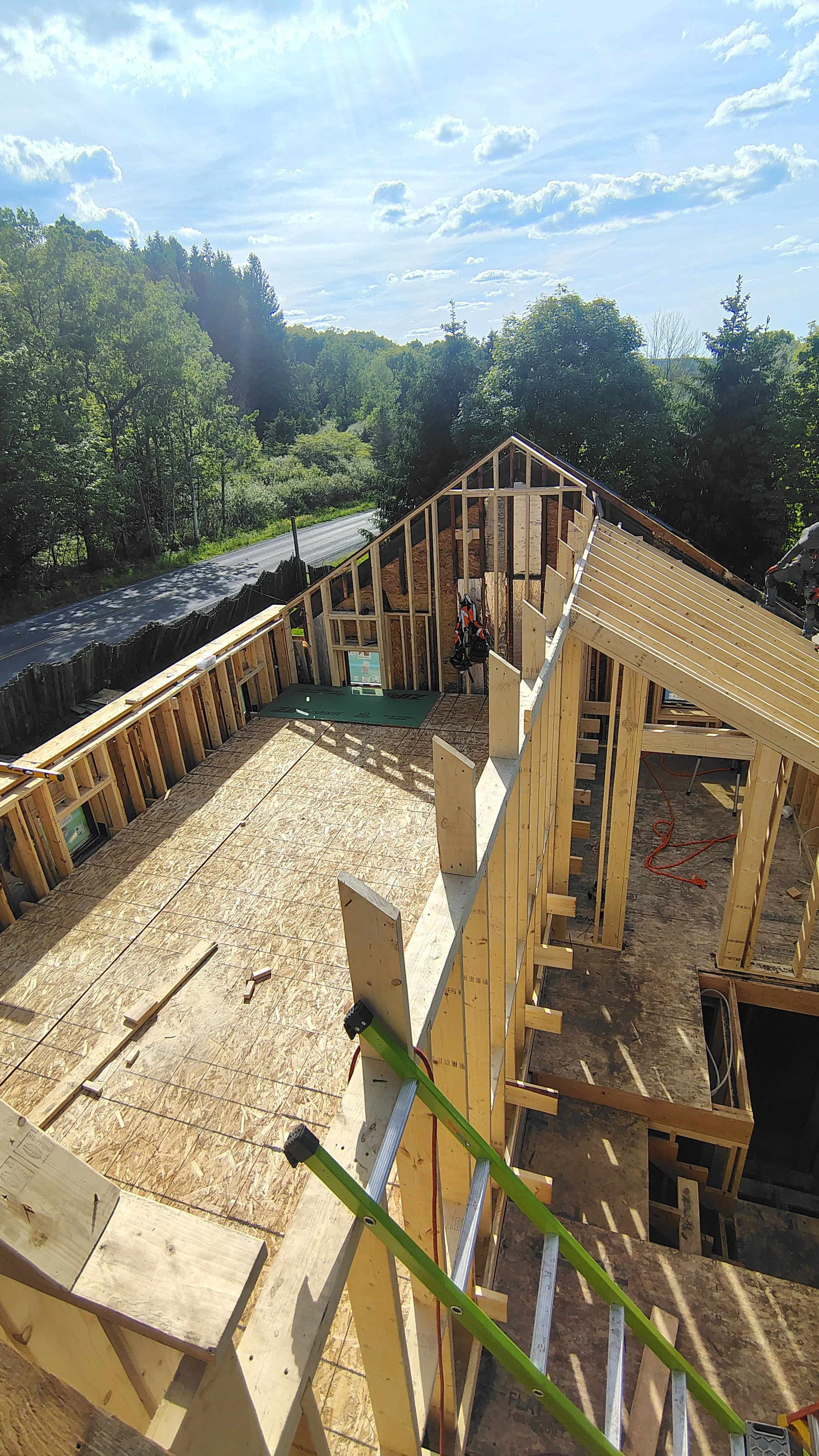 Wood-framed residential structure with OSB sheathing and pitched roof framing during construction phase