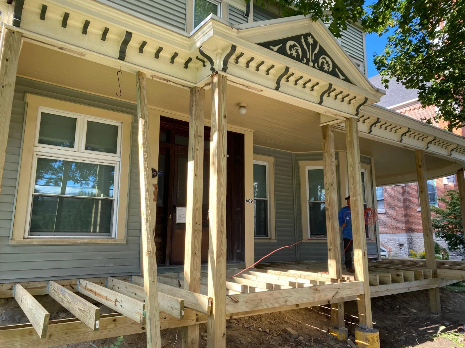 New wooden porch with posts, brackets, and decking under gable roof with decorative trim