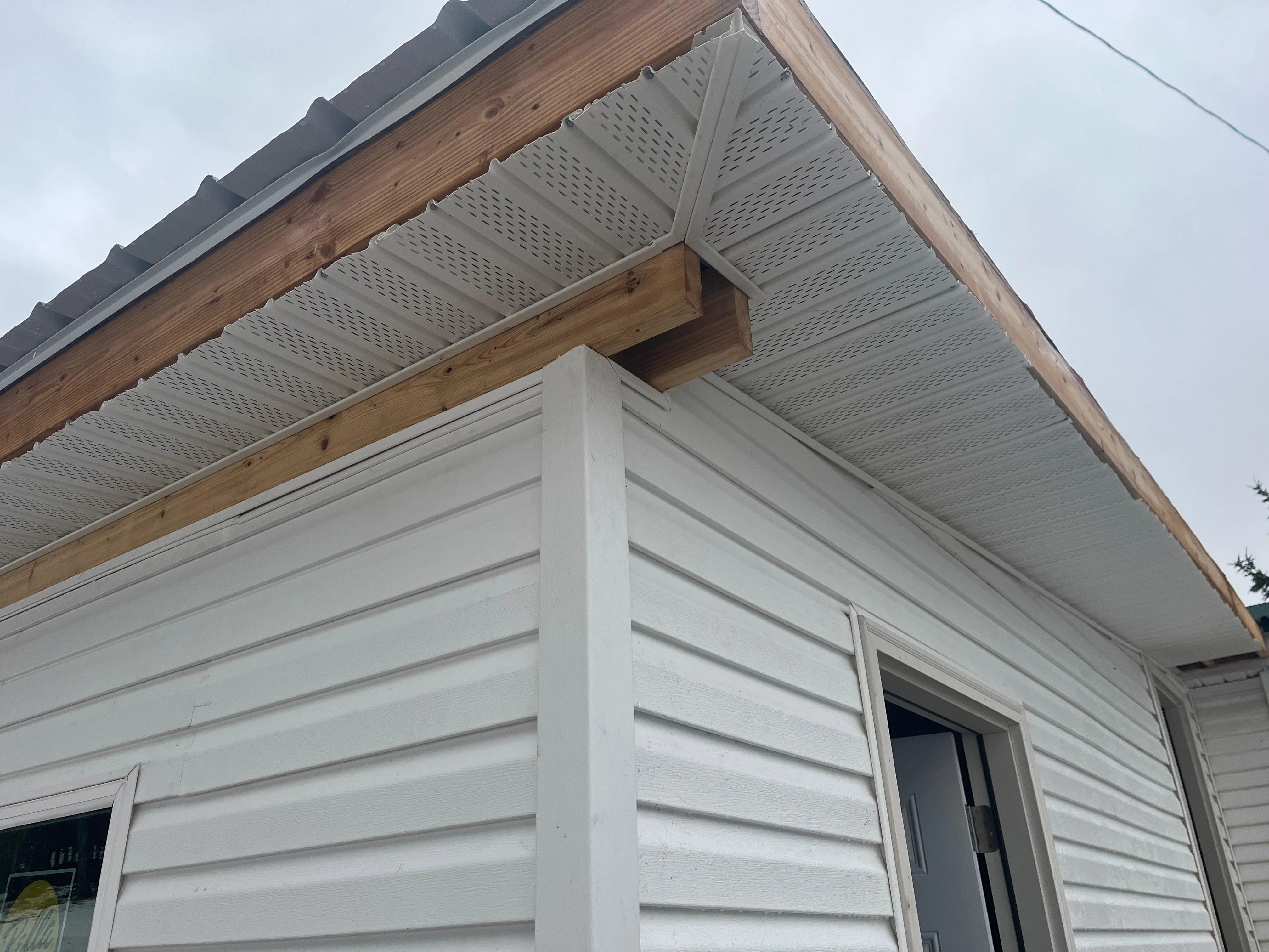 Perforated aluminum soffit with wood beam accents and white fascia on horizontal siding, Vestal NY