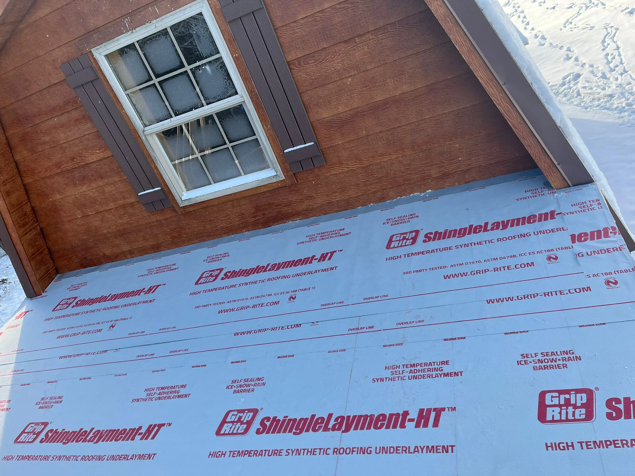 Grip-Rite synthetic roofing underlayment installed on roof deck with window and dormer visible