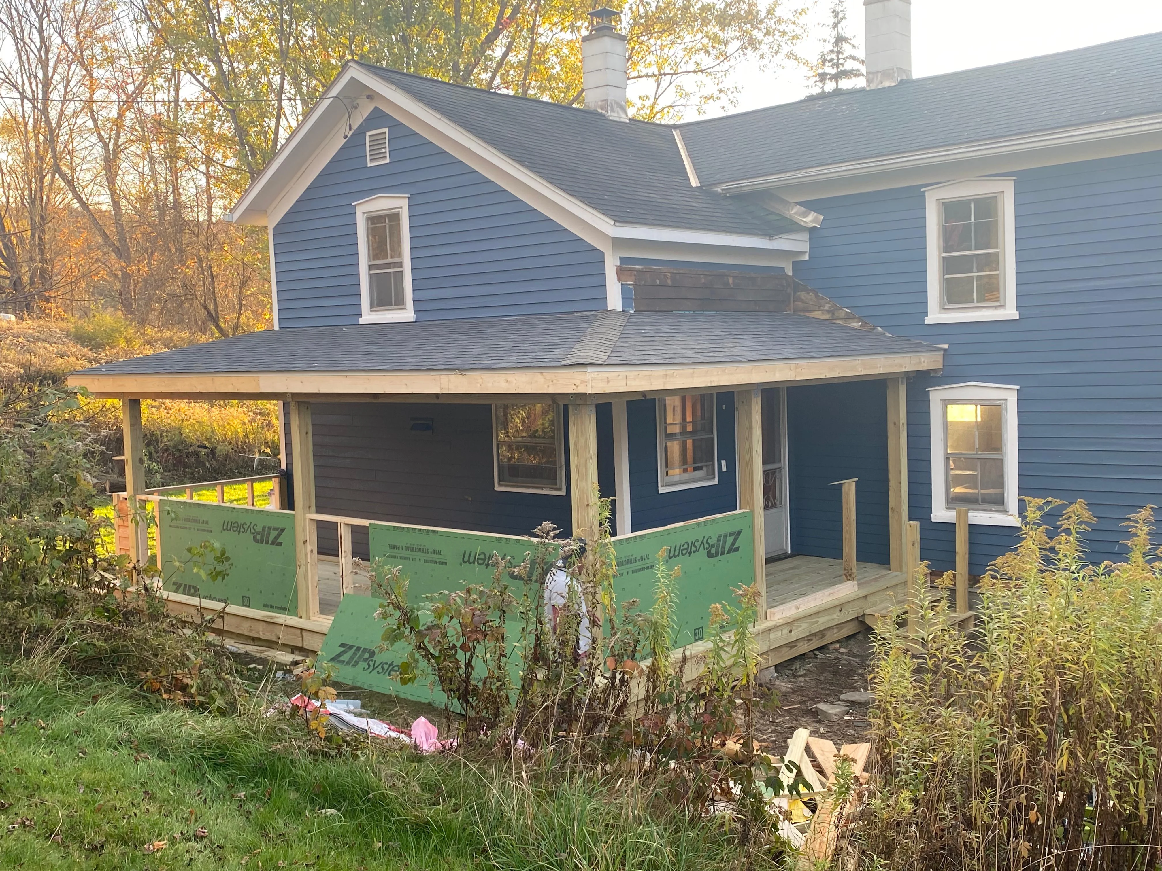 Front porch addition with wood framing, new decking, and roof structure under construction