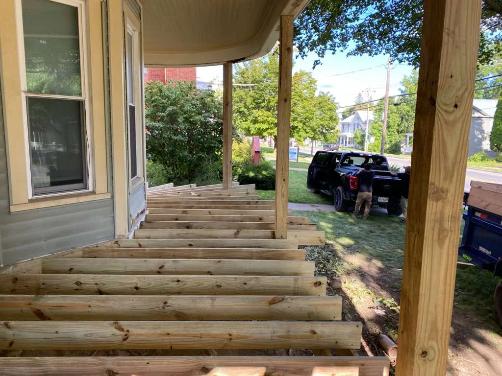 Pressure-treated wood deck framing with joists, beams, and support posts under construction