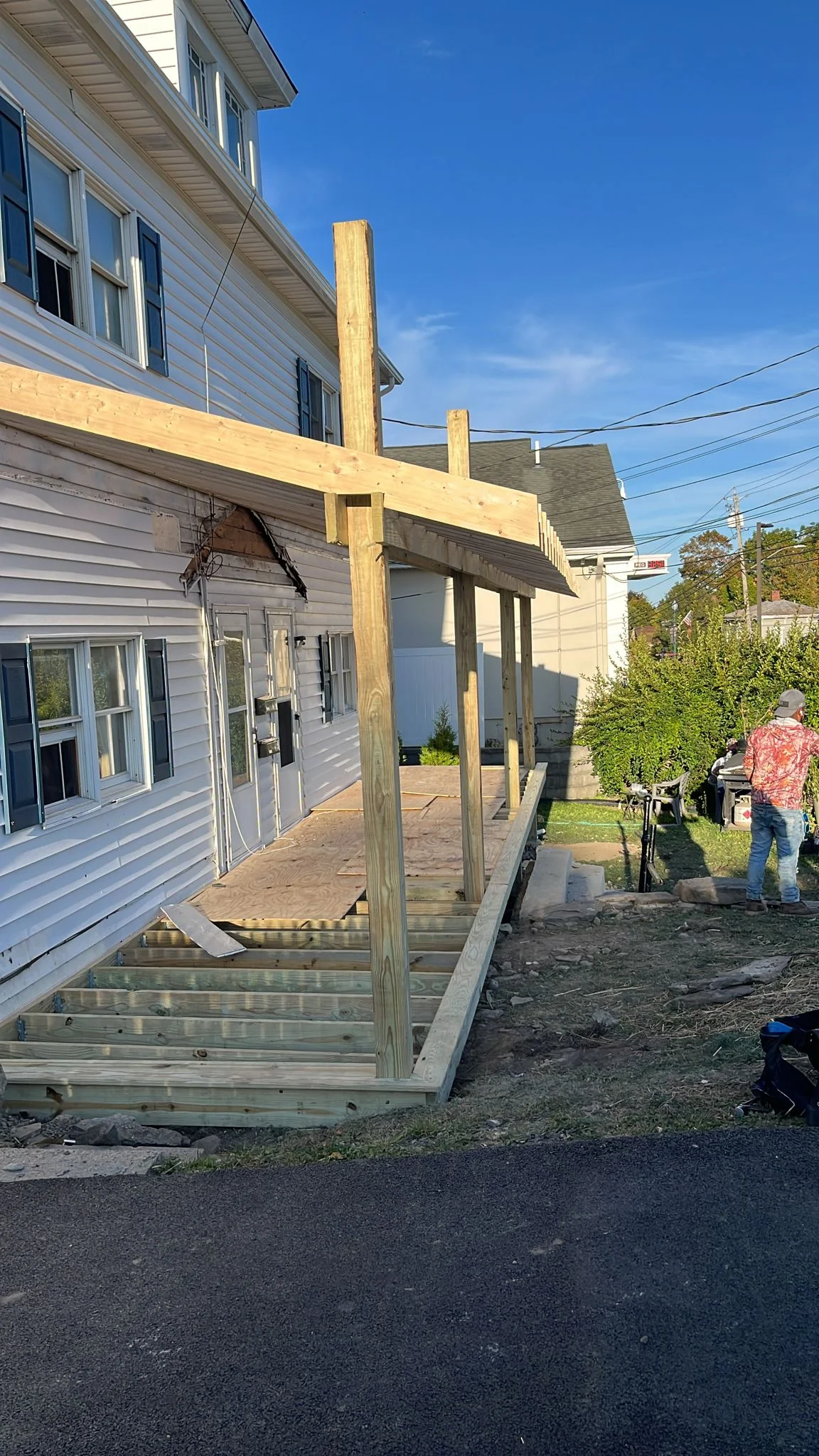 Pressure-treated wood deck and pergola with vertical posts under construction on residential property