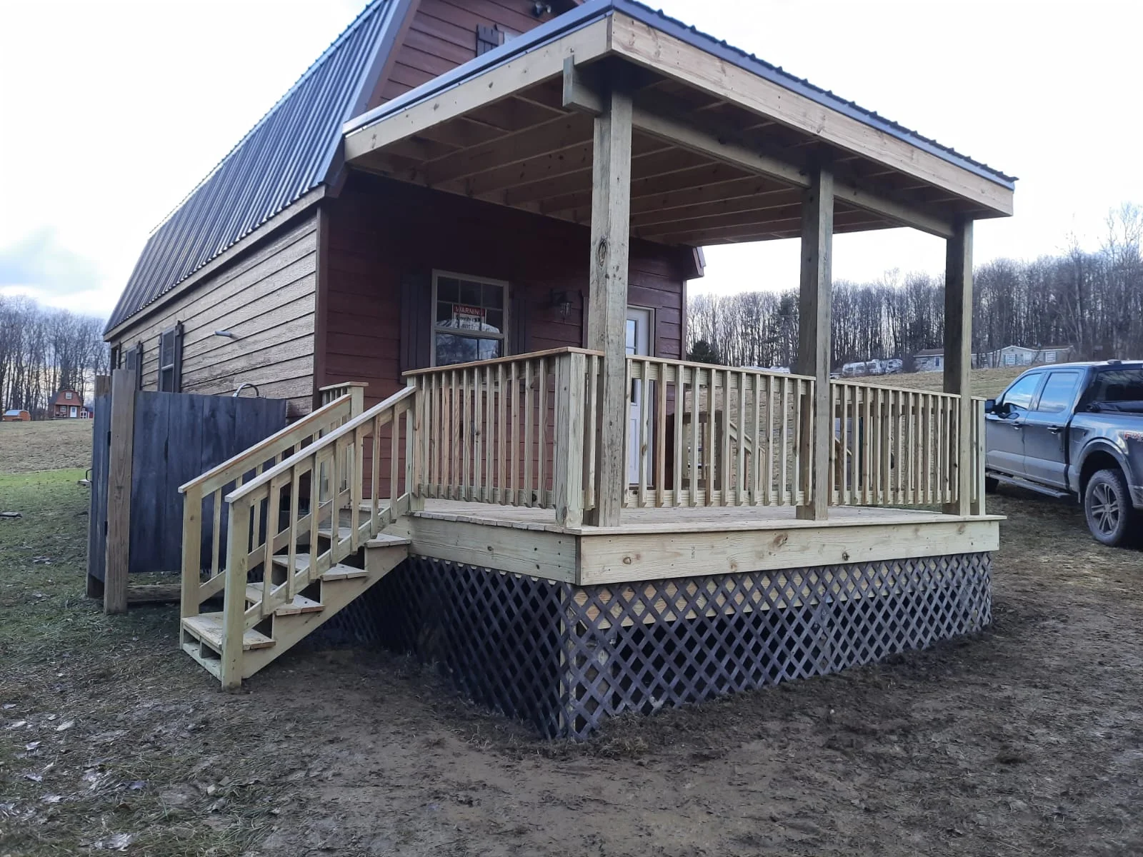 Pressure-treated wood deck with railings and lattice skirting under covered porch structure