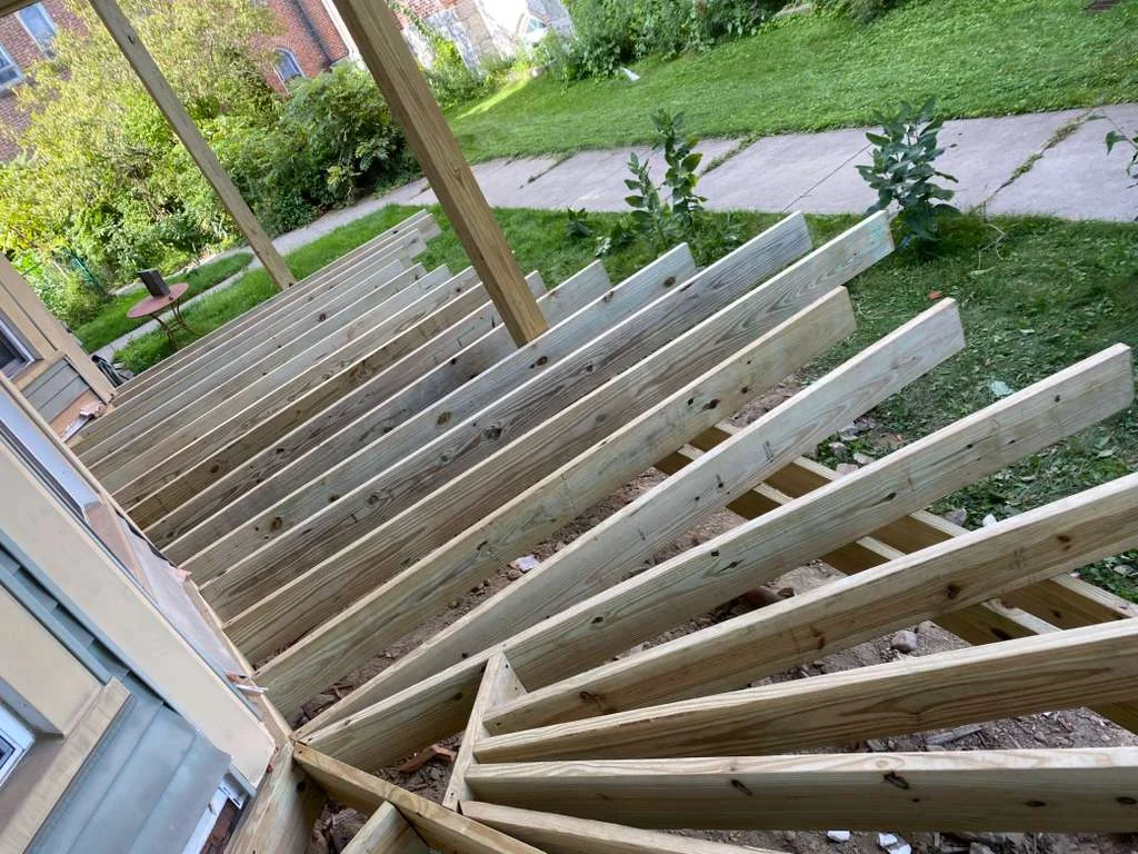 Pressure-treated wood deck framing with parallel joists and support beams during construction