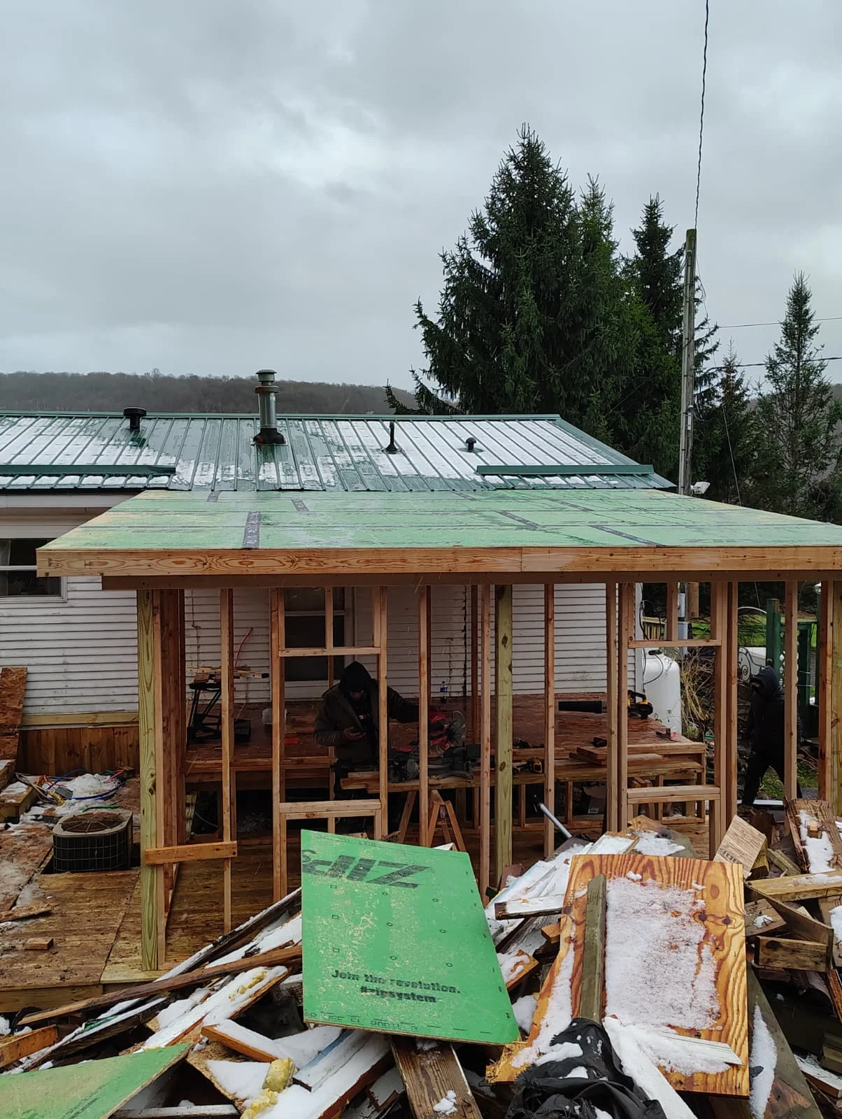 Wood-framed residential addition with standing seam metal roof and multi-pane window installation