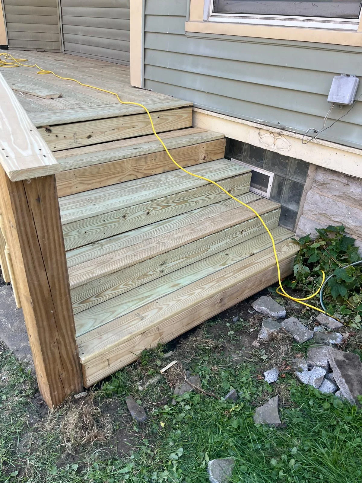 Multi-level pressure-treated wood deck with stairs and wooden railing under construction